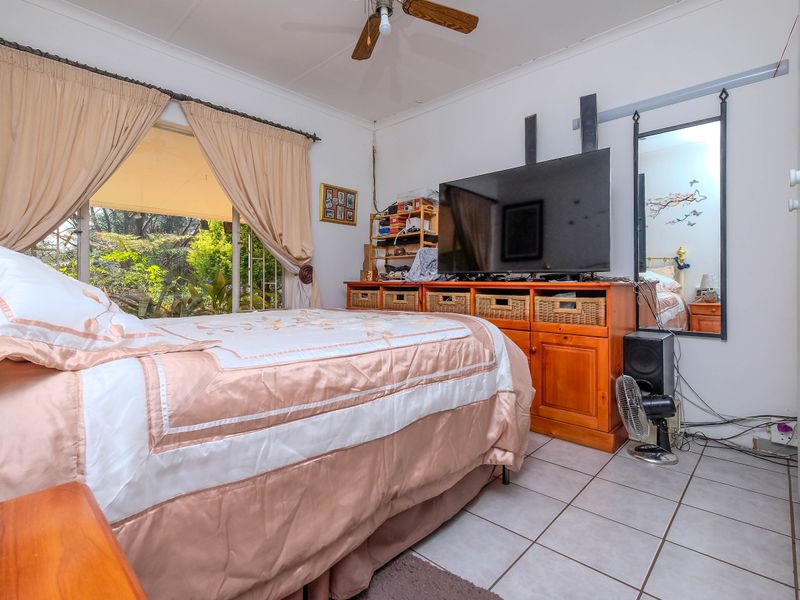 A bedroom featuring tiled flooring, a ceiling fan, and a sliding glass door providing access to the outdoor area.