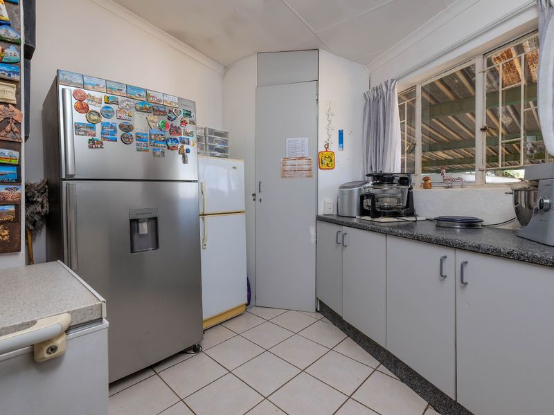 A functional scullery area featuring tiled flooring, laminate countertops, and built-in cabinetry, providing additional storage and workspace adjacent to the main kitchen.