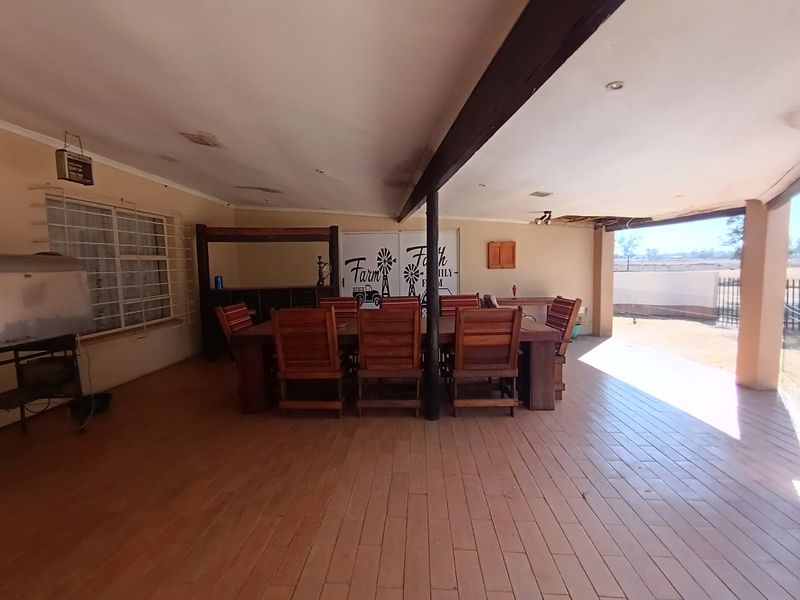 Spacious covered patio area featuring tiled flooring and exposed timber beams, requiring some ceiling maintenance and cosmetic updates to enhance the outdoor living space.