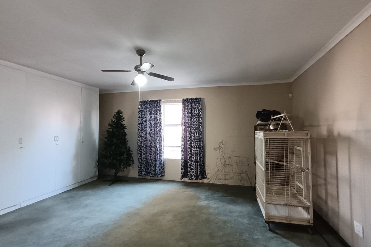 Spacious bedroom featuring built-in cupboards, a ceiling fan, and carpeted flooring. The room offers a neutral canvas ready for updates and personalization.