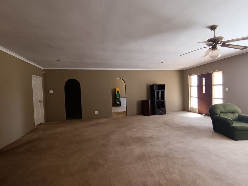 Spacious living area featuring arched doorways, a ceiling fan, and neutral wall tones, offering a versatile layout for comfortable family living.