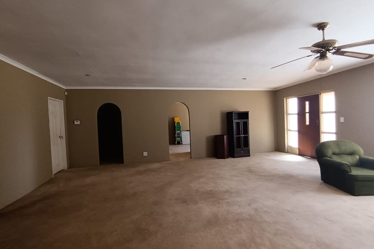 Spacious living area featuring arched doorways, a ceiling fan, and neutral wall tones, offering a versatile layout for comfortable family living.