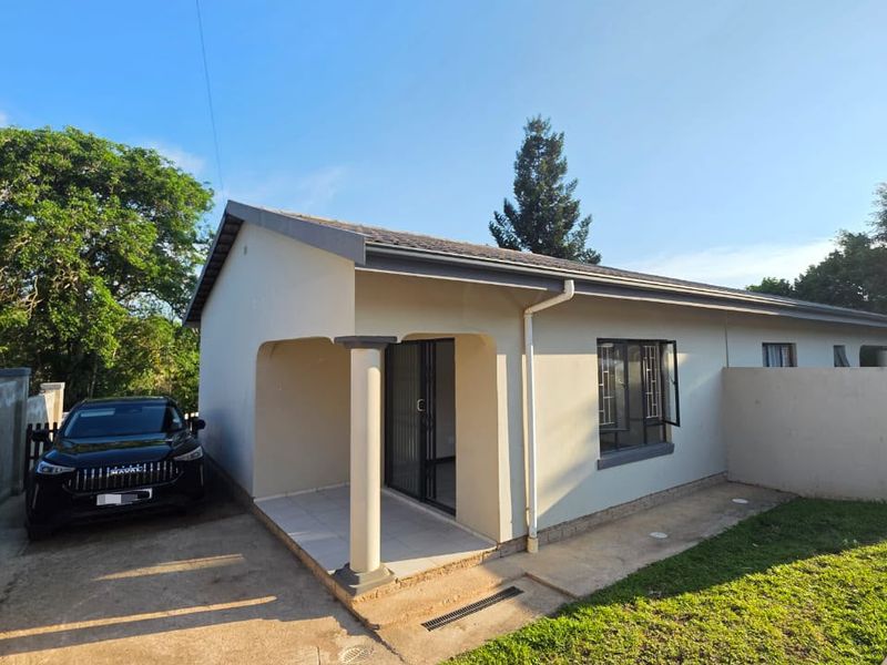 Front view of a cottage featuring a covered patio, concrete driveway, and a well-maintained exterior facade with secure access.