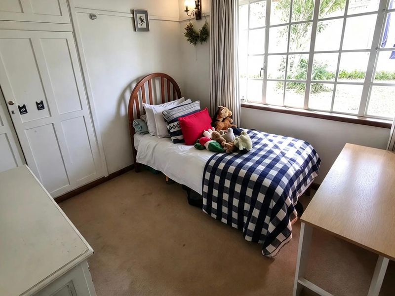 A cozy bedroom featuring a large multi-pane window, built-in wardrobe storage, and carpeted flooring.