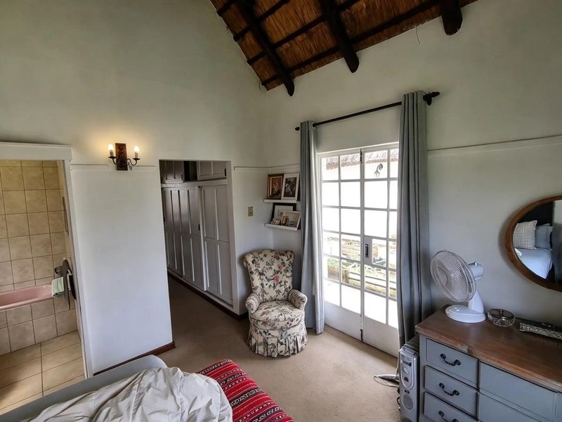 A bedroom featuring a high thatched ceiling, built-in storage, and direct access to an en-suite bathroom through a doorway.