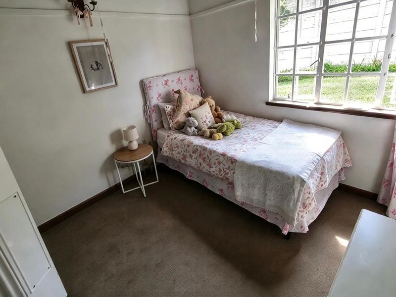 A cozy bedroom featuring carpeted flooring, a classic multi-pane window, and a built-in cupboard, offering a comfortable and functional living space.