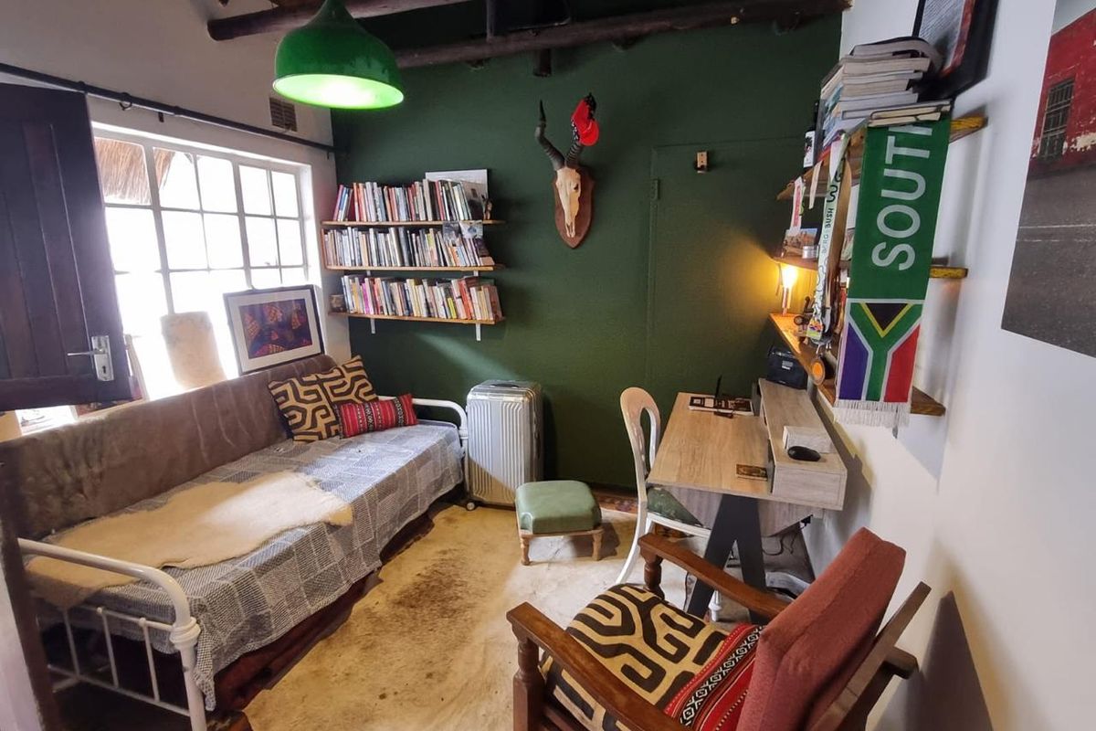 A cozy bedroom featuring exposed timber ceiling beams, built-in shelving, and a multi-pane window, offering a rustic and character-filled living space.