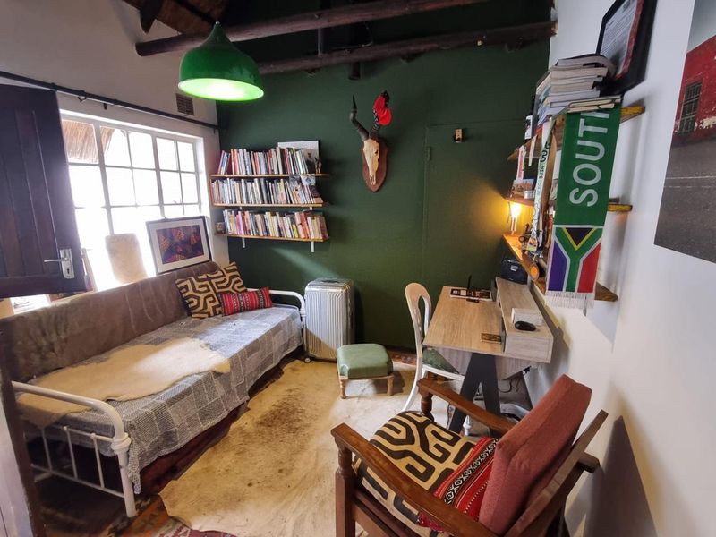 A cozy bedroom featuring exposed timber ceiling beams, built-in shelving, and a multi-pane window, offering a rustic and character-filled living space.