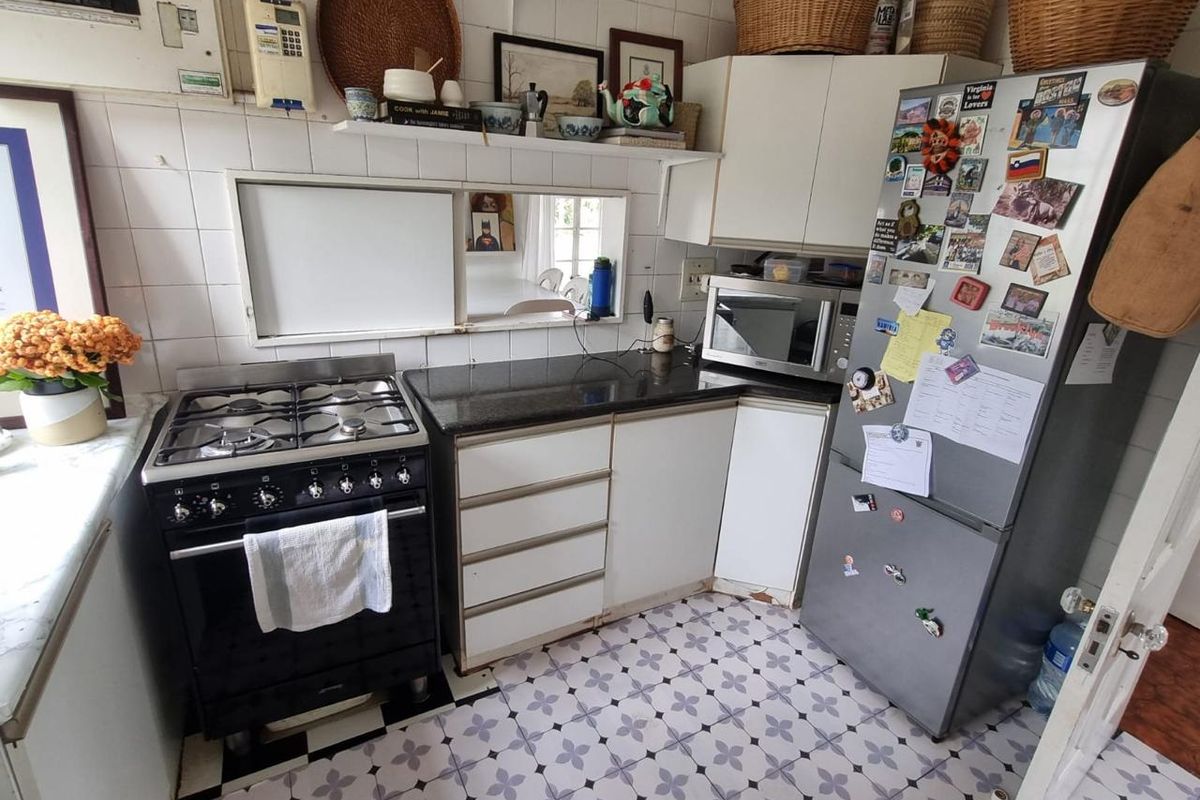 A compact kitchen featuring a gas stove, granite countertops, tiled backsplash, and patterned floor tiles, offering a functional layout with potential for modern updates.