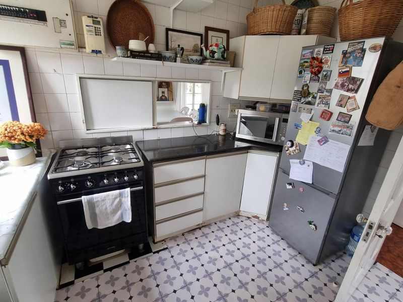 A compact kitchen featuring a gas stove, granite countertops, tiled backsplash, and patterned floor tiles, offering a functional layout with potential for modern updates.