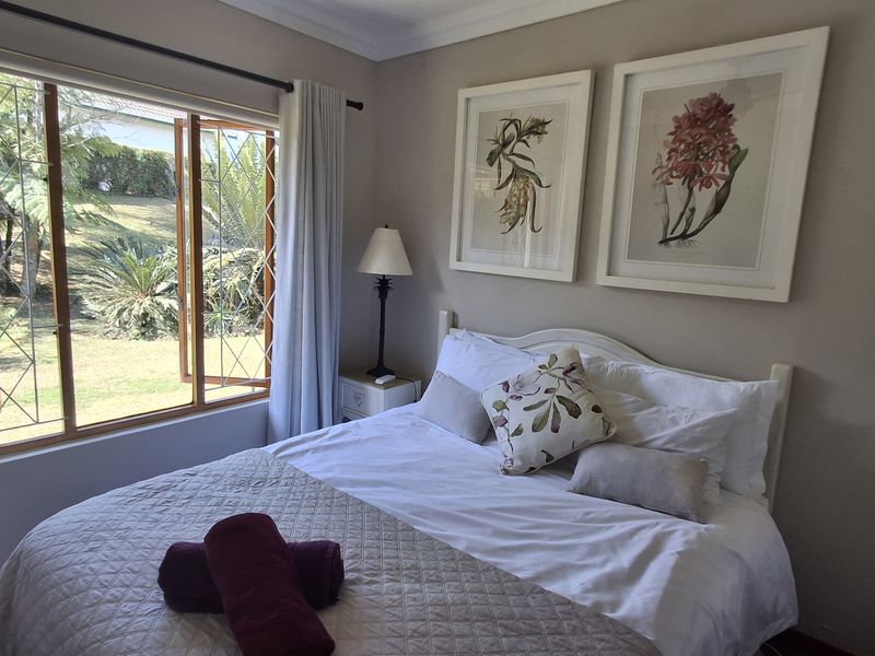 A well-maintained bedroom featuring leaded glass timber windows with garden views and decorative ceiling coving.