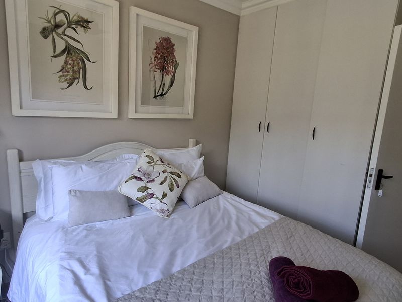 A well-maintained bedroom featuring neutral wall tones and practical built-in cupboards, providing a comfortable and functional living space.