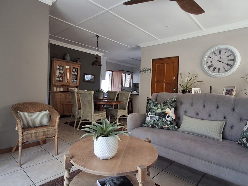 An open-plan living and dining area featuring tiled flooring, decorative ceiling paneling, and neutral wall tones, creating a cohesive and functional living space.