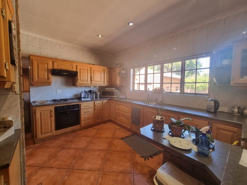 A functional kitchen featuring traditional wooden cabinetry, a built-in oven with gas hob, tiled backsplash, and ample counter space with a breakfast nook.