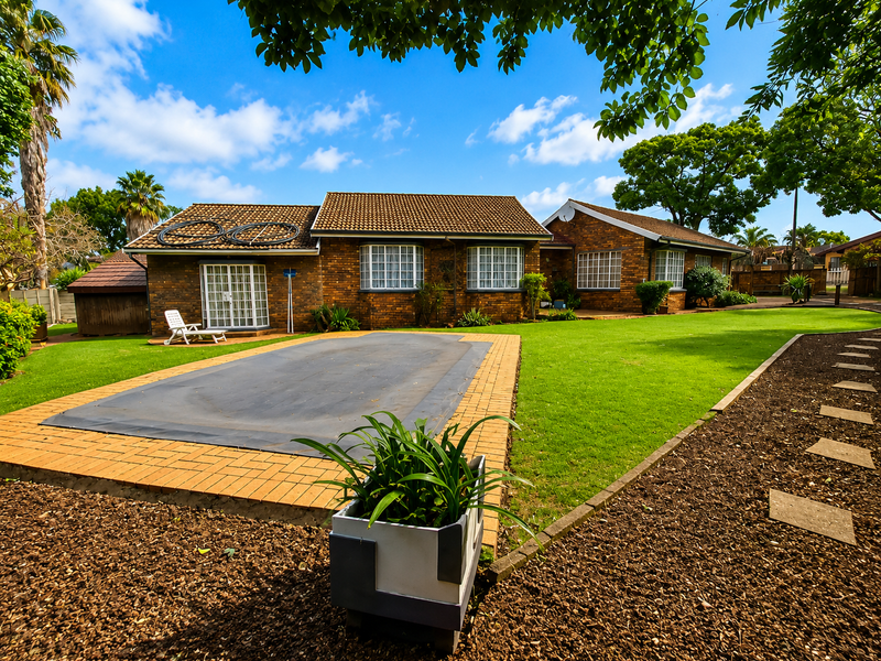 Rear view of a brick house featuring a well-maintained lawn, a swimming pool with a cover, and paved outdoor areas.