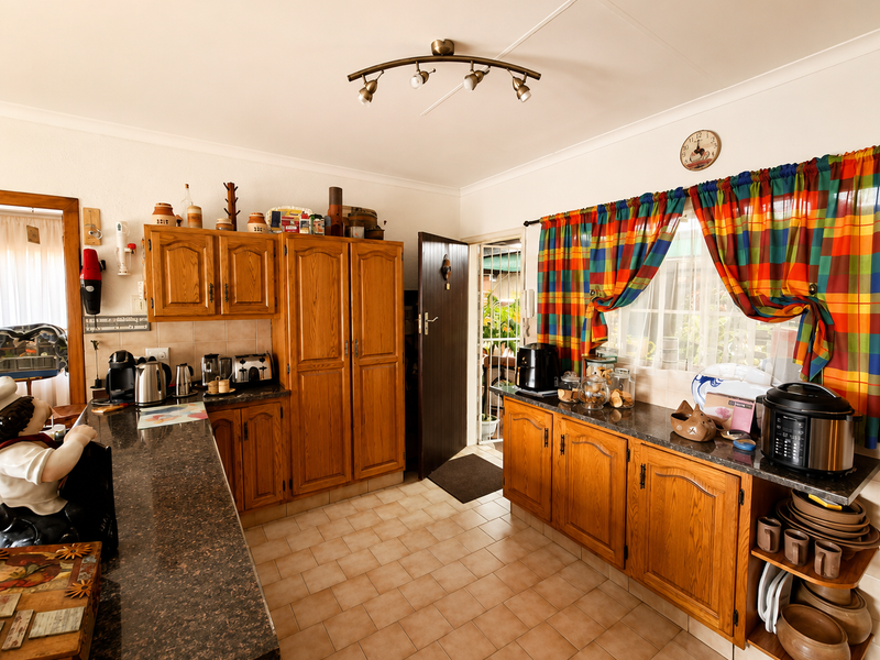 A functional kitchen featuring traditional wooden cabinetry, granite countertops, tiled flooring, and a tiled backsplash, offering a classic layout with direct outdoor access.