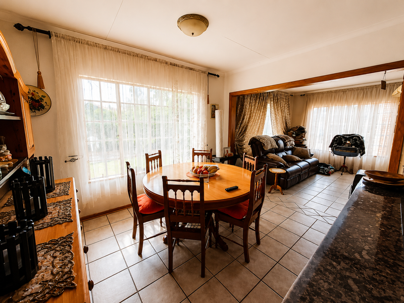 Spacious open-plan living and dining area featuring tiled flooring, large windows with natural light, and a functional kitchen counter space.