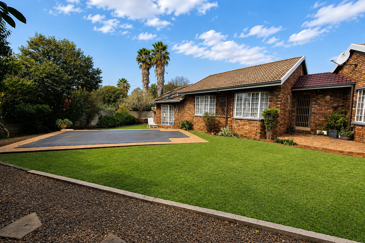 A well-maintained rear garden featuring a swimming pool with a cover, paved patio area, and classic brick facade house exterior.