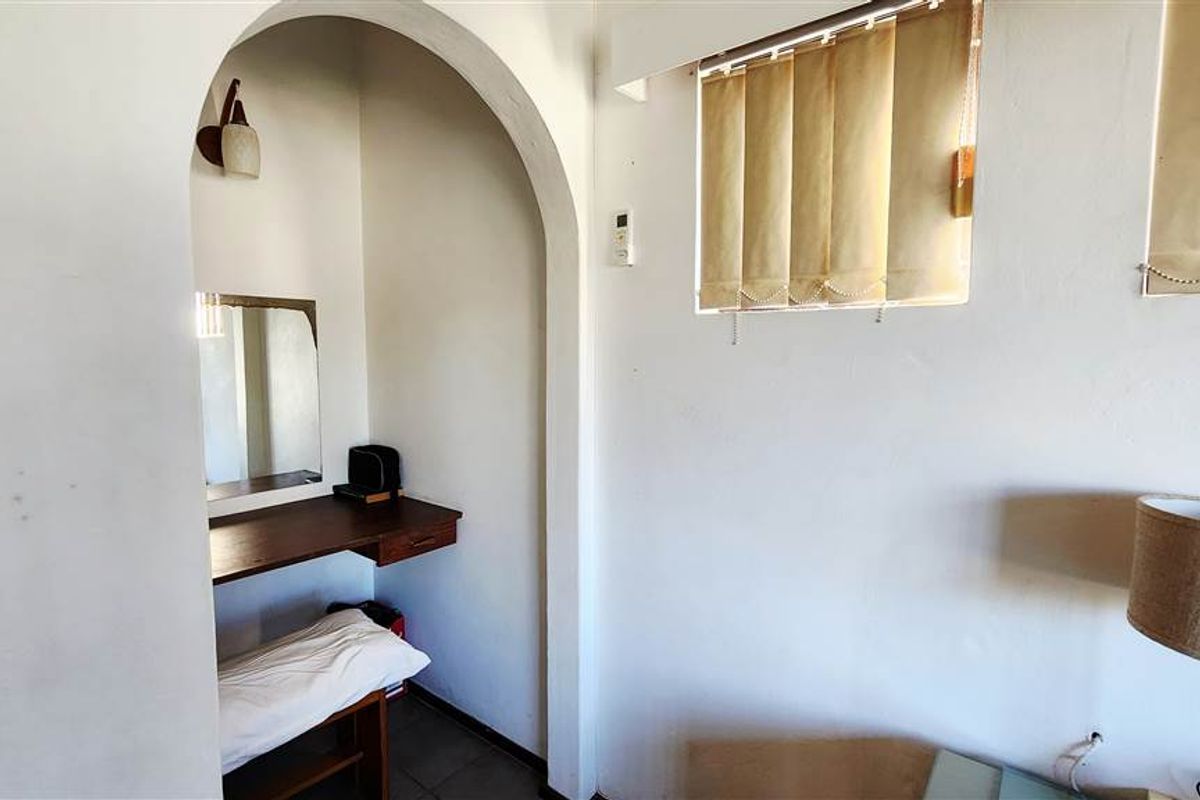 A bedroom featuring a built-in arched vanity alcove with a wooden desk and wall-mounted lighting.