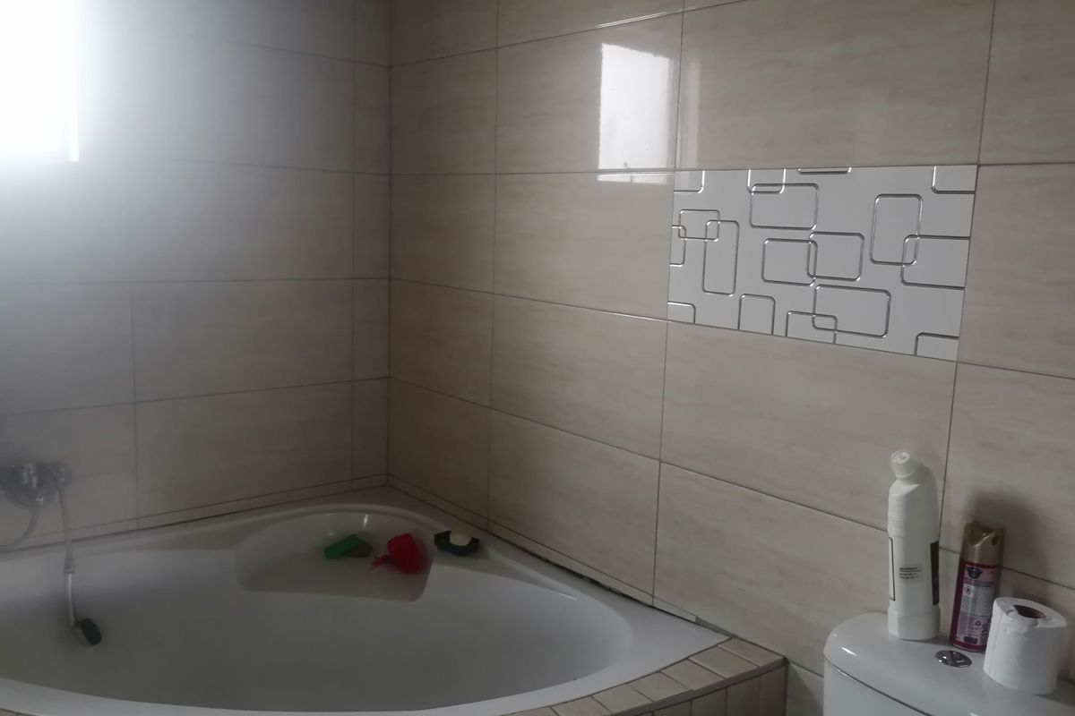 A bathroom featuring a corner bathtub with tiled surround and decorative wall accent tiles.