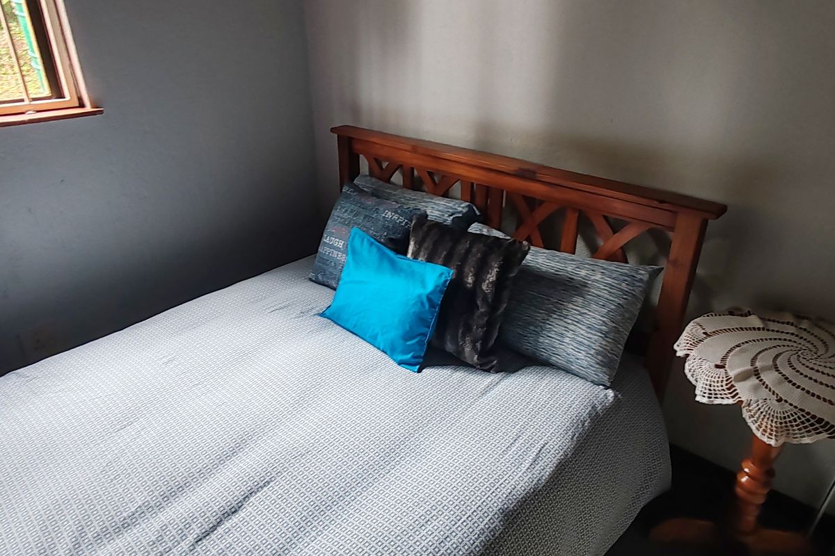 A bedroom featuring a window with security bars, providing natural light and a view of the exterior.