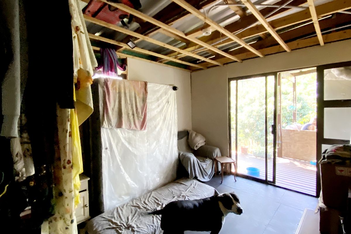 A room featuring exposed ceiling rafters and sliding glass doors leading to an outdoor deck area.