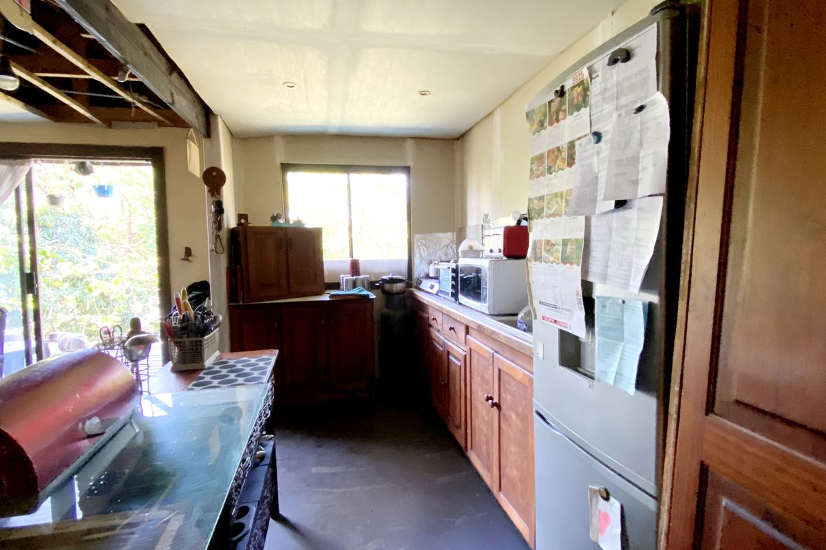 A compact kitchen area featuring wooden cabinetry, a sliding glass door leading to the outdoors, and exposed ceiling joists in the adjacent living space.