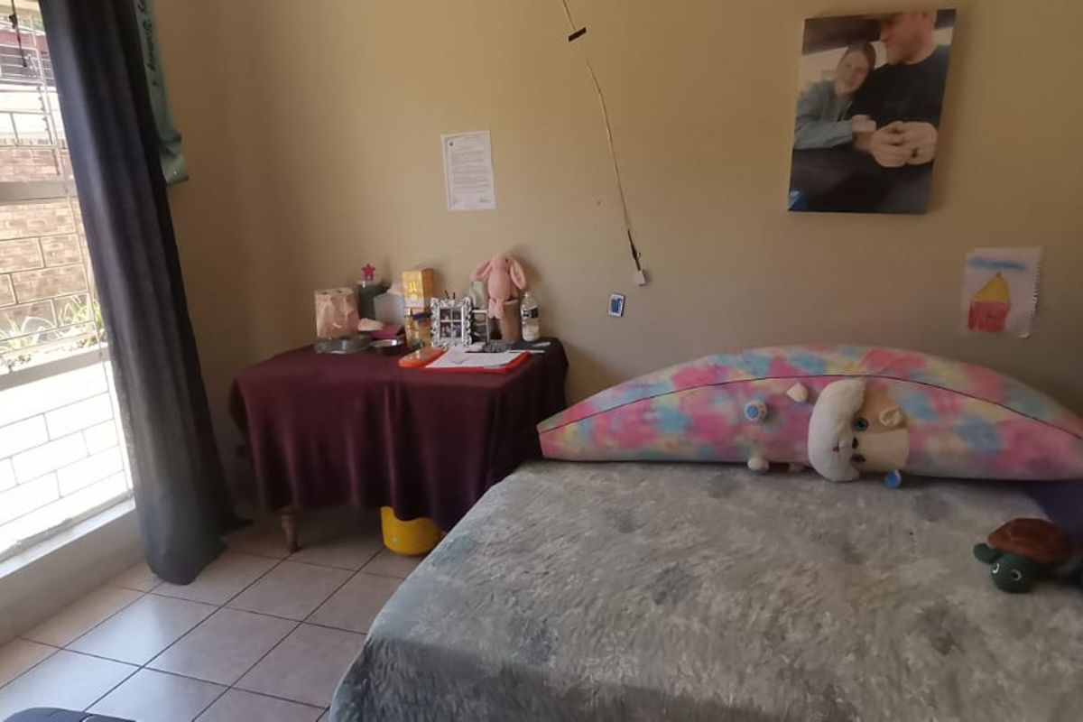 A bedroom featuring tiled flooring and a window with security bars, requiring minor maintenance to address exposed electrical wiring.