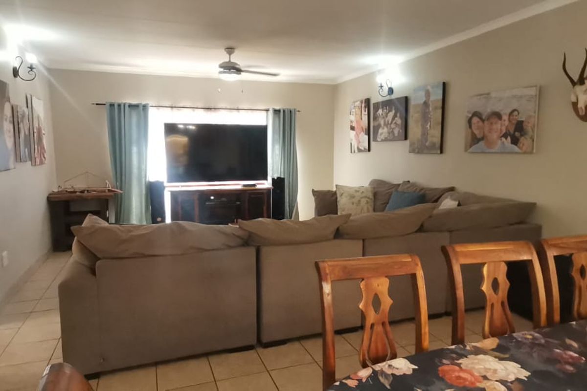 A spacious living room featuring tiled flooring, a ceiling fan, and an arched entryway, providing a comfortable and functional family living space.