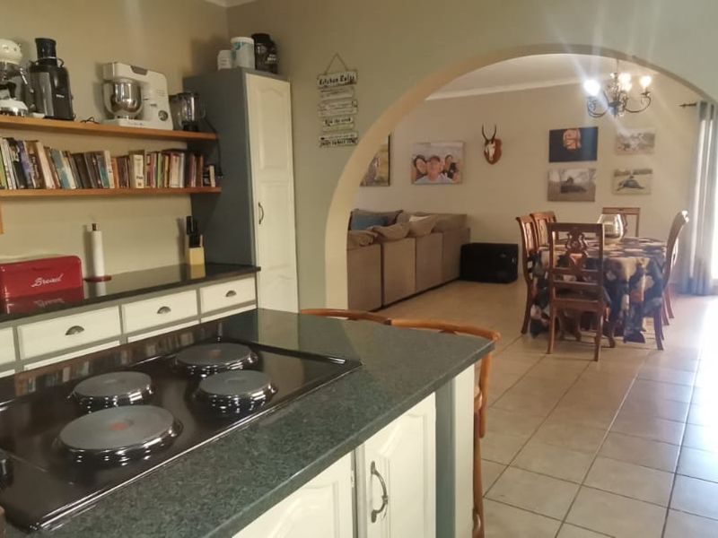Open plan kitchen and dining area featuring built-in cabinetry, electric hob, and tiled flooring, connected by a distinctive arched doorway.