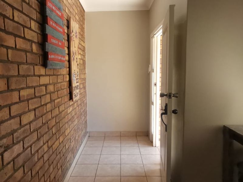 A bright entrance hall featuring a characterful exposed brick feature wall and neutral tiled flooring, leading directly into the home.