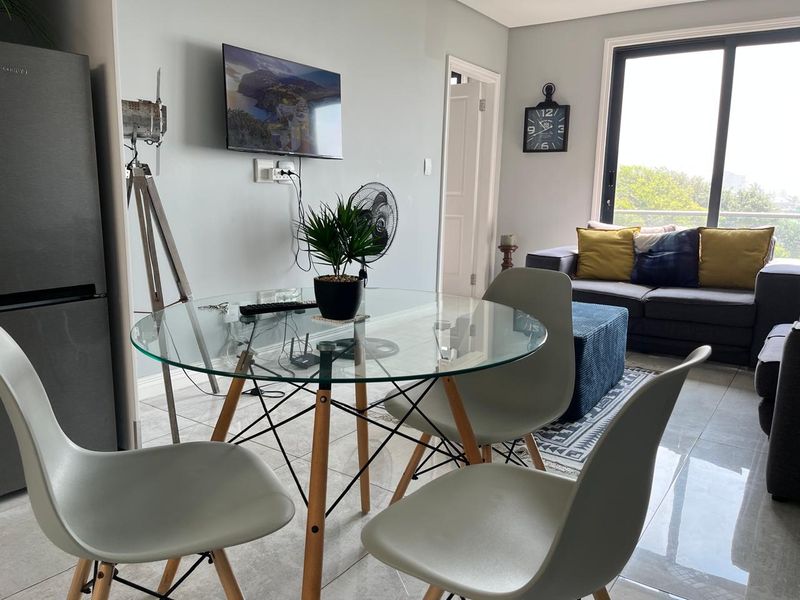 An open-plan living and dining area featuring tiled flooring and a sliding glass door providing natural light and access to the exterior.