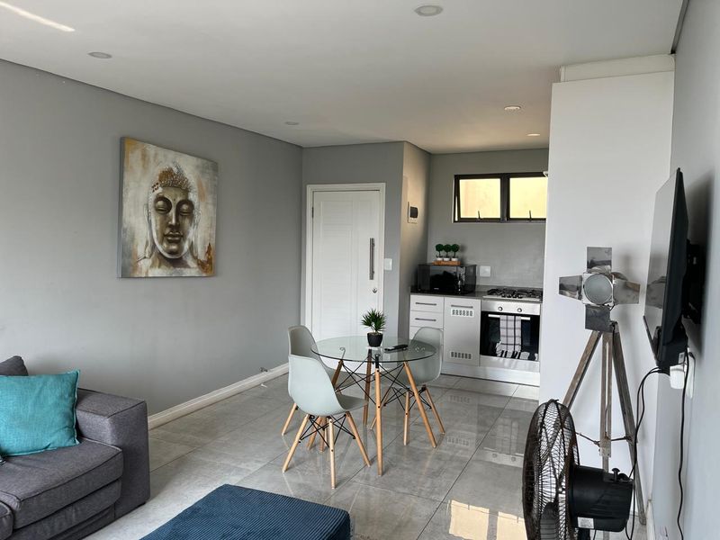 Modern open-plan living area featuring tiled floors, recessed lighting, and a compact kitchen equipped with a built-in oven and gas hob.