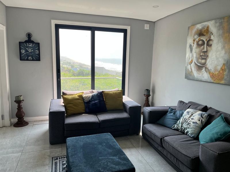 A bright living room featuring large sliding glass doors that offer scenic coastal views and provide ample natural light.