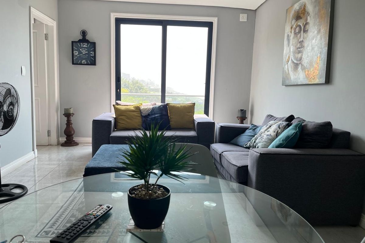A bright living room featuring large sliding glass doors that provide natural light and access to an outdoor area, complemented by neutral tiled flooring.