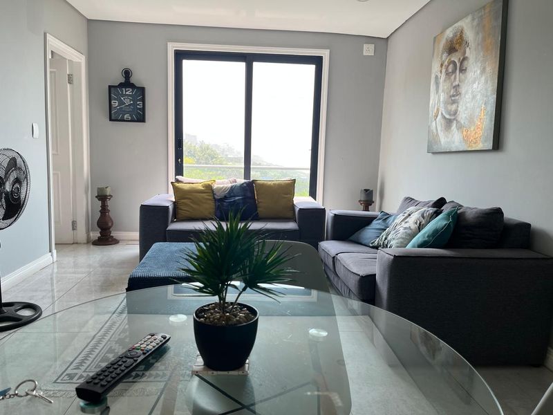 A bright living room featuring large sliding glass doors that provide natural light and access to an outdoor area, complemented by neutral tiled flooring.