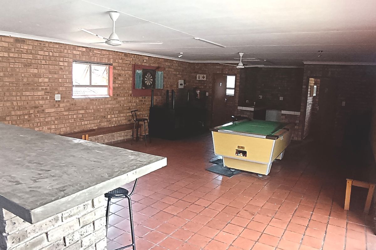 Spacious entertainment area featuring a built-in brick bar, terracotta tiled flooring, and large sliding glass doors opening to the exterior.