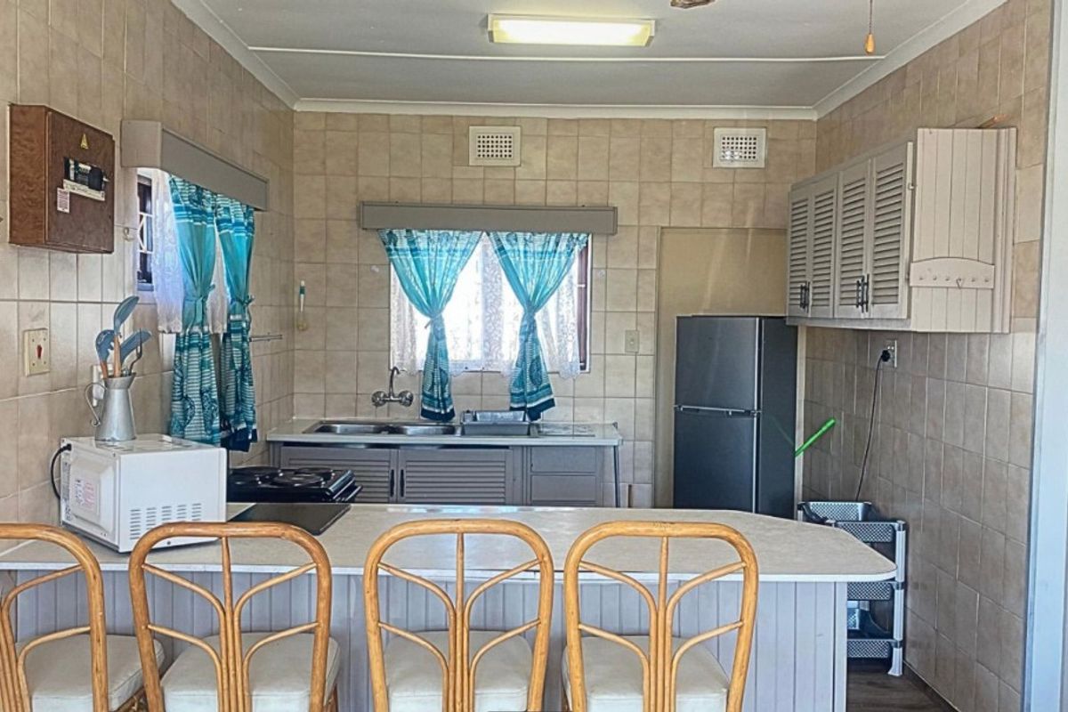 A functional kitchen featuring tiled walls, built-in cabinetry, a double sink, and a breakfast counter, offering a practical layout for daily meal preparation.