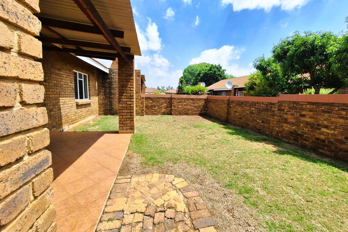 A private rear garden featuring a covered patio with tiled flooring, brick boundary walls, and a small paved area, offering potential for outdoor landscaping.