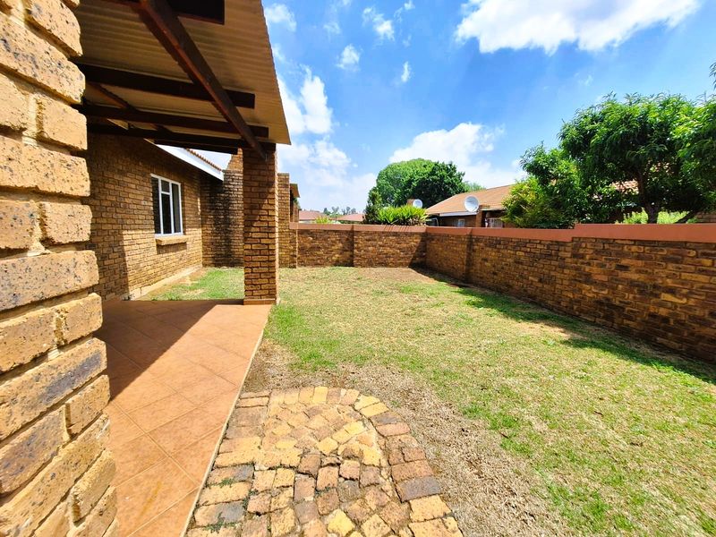 A private rear garden featuring a covered patio with tiled flooring, brick boundary walls, and a small paved area, offering potential for outdoor landscaping.