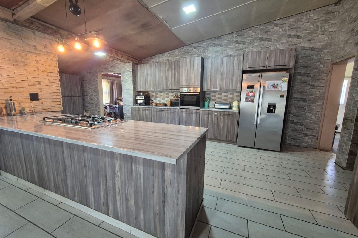 Spacious modern kitchen featuring a large island with a gas hob, extensive built-in cabinetry, and stylish stone veneer wall accents.