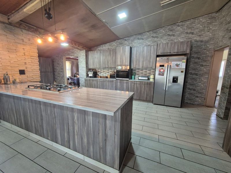 Spacious modern kitchen featuring a large island with a gas hob, extensive built-in cabinetry, and stylish stone veneer wall accents.