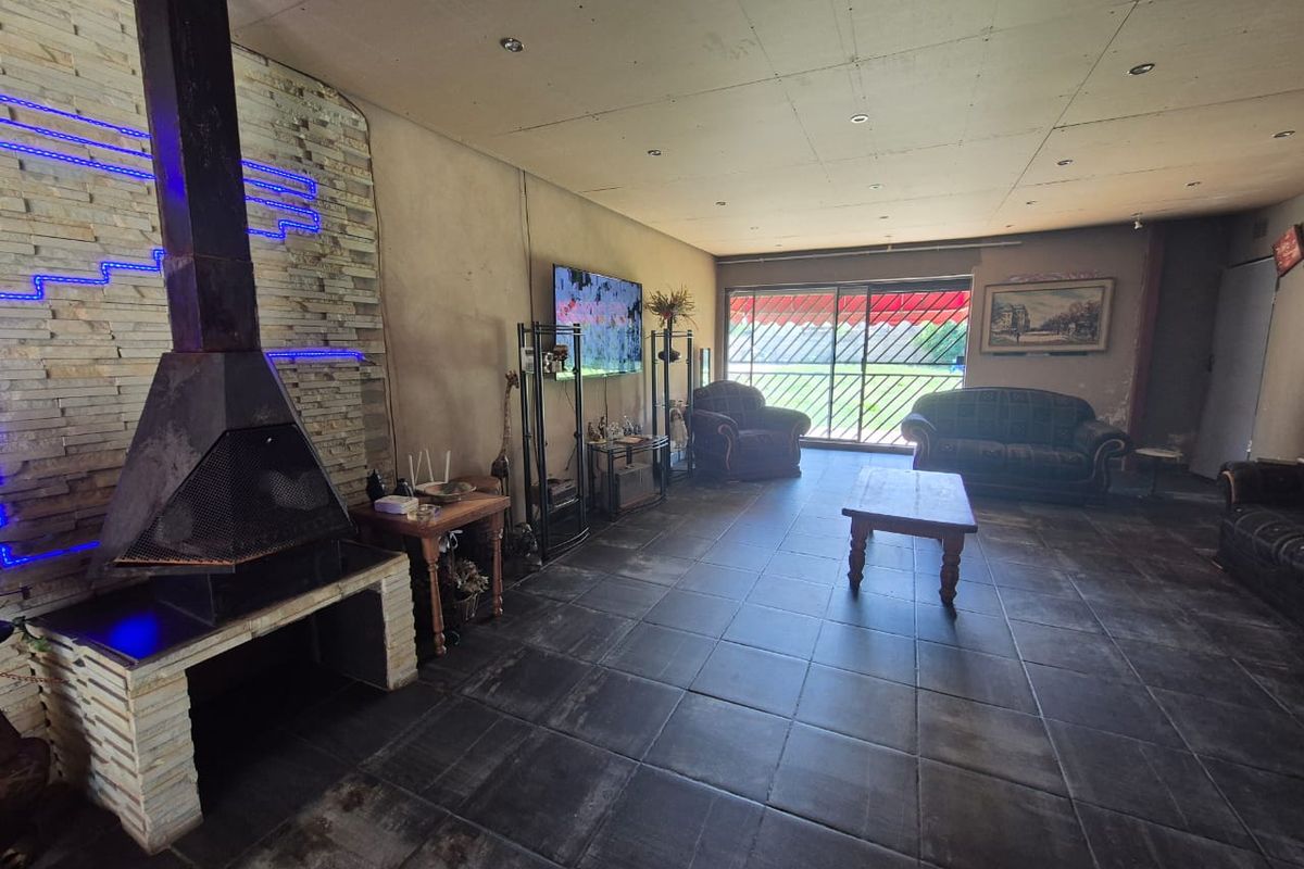 Spacious living room featuring a stone fireplace, dark tiled flooring, and large sliding doors leading to the exterior.