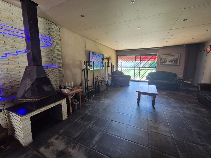 Spacious living room featuring a stone fireplace, dark tiled flooring, and large sliding doors leading to the exterior.