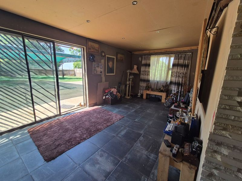 Living area featuring dark tiled flooring, a stone accent wall, and large sliding glass doors providing direct access to the outdoor patio area.