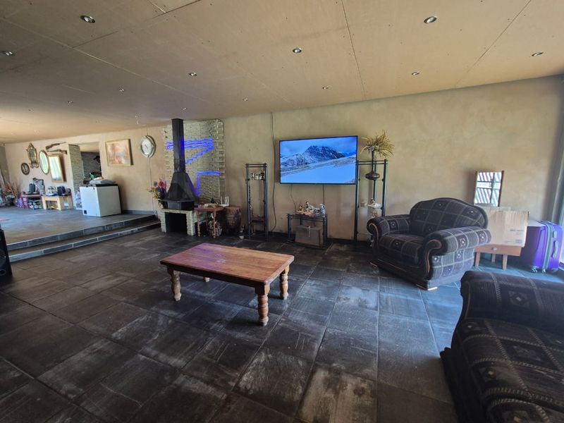 Spacious living room featuring dark stone tile flooring, a central freestanding fireplace, and recessed ceiling lighting.