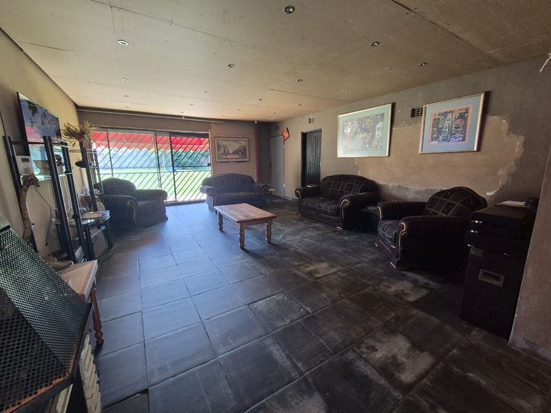 Spacious living room featuring tiled flooring, recessed lighting, and a sliding glass door leading to the exterior, requiring cosmetic updates to the walls.