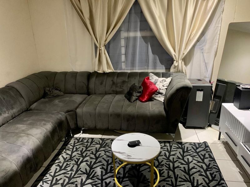 A living room area featuring tiled flooring and a window with curtains.