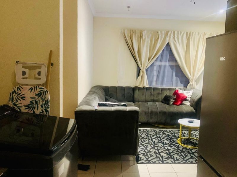 An open-plan living area featuring tiled flooring and neutral wall finishes, providing a functional space for relaxation and daily activities.