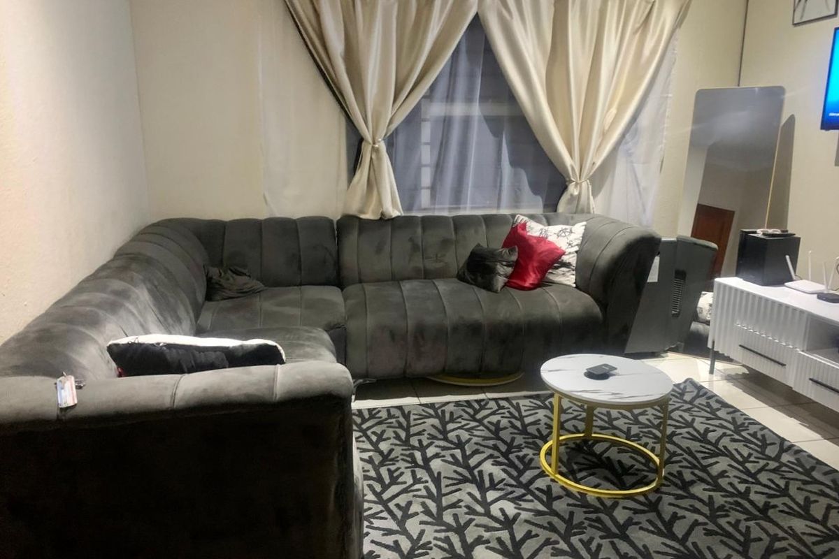 A living room space featuring tiled flooring and a window with curtains.